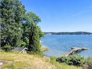 A lakeside property with a dock, a small building, and dense trees. - 4 Person Holiday Home in Akersberga (Akersberga)