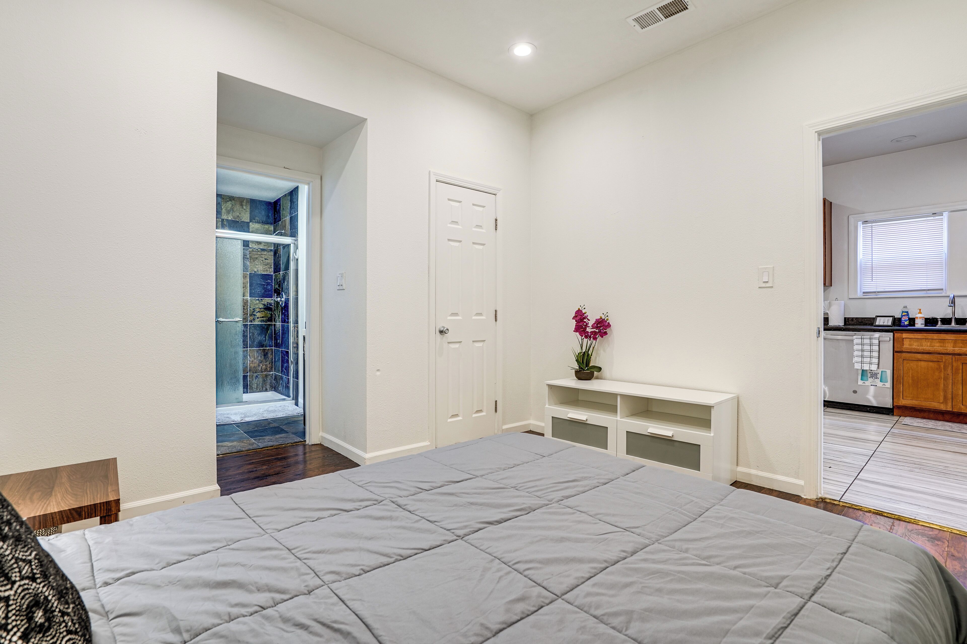 Un dormitorio con una cama grande, un vestidor y vistas a la cocina.