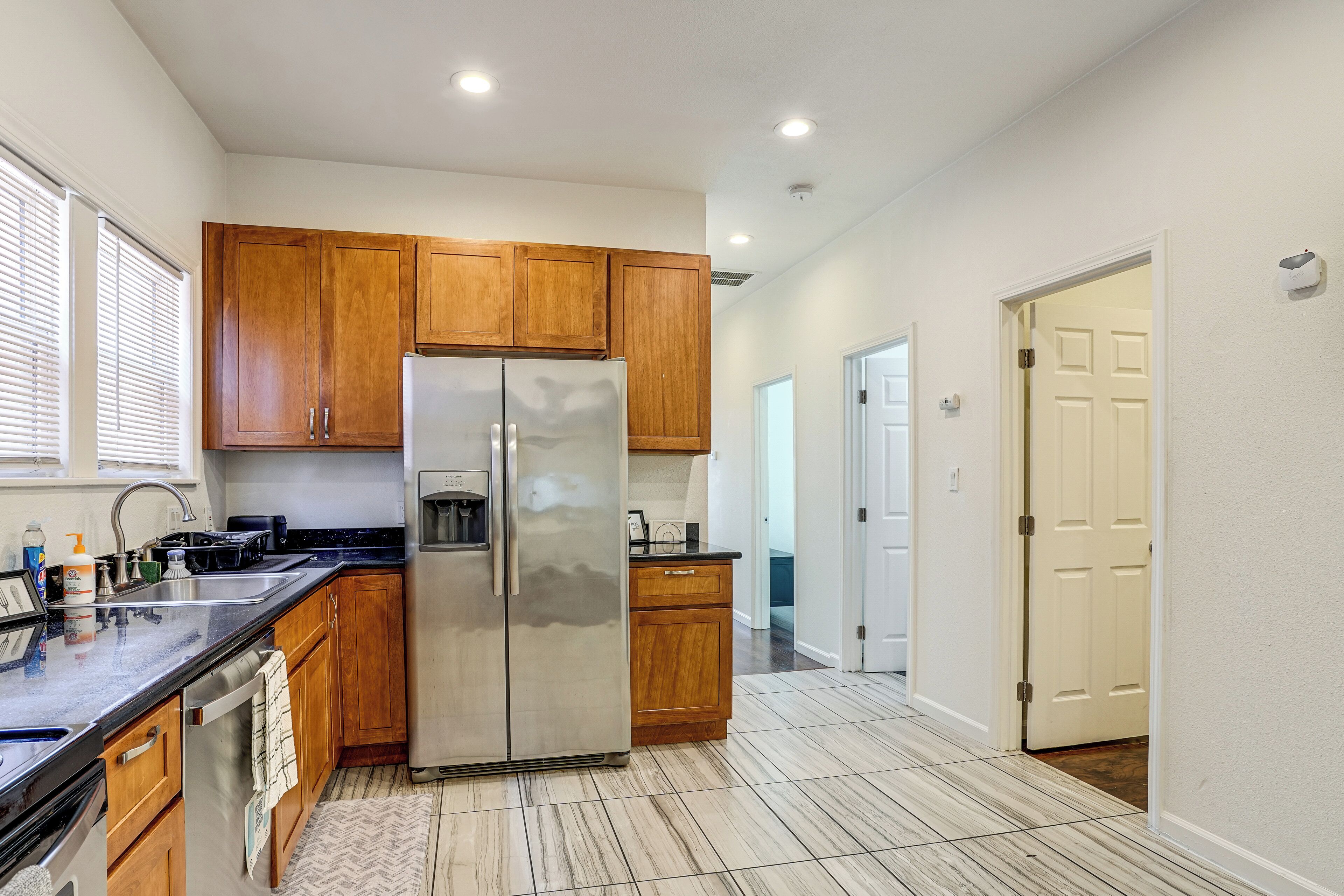 Una cocina moderna con armarios de madera, un refrigerador de acero inoxidable y una encimera negra.