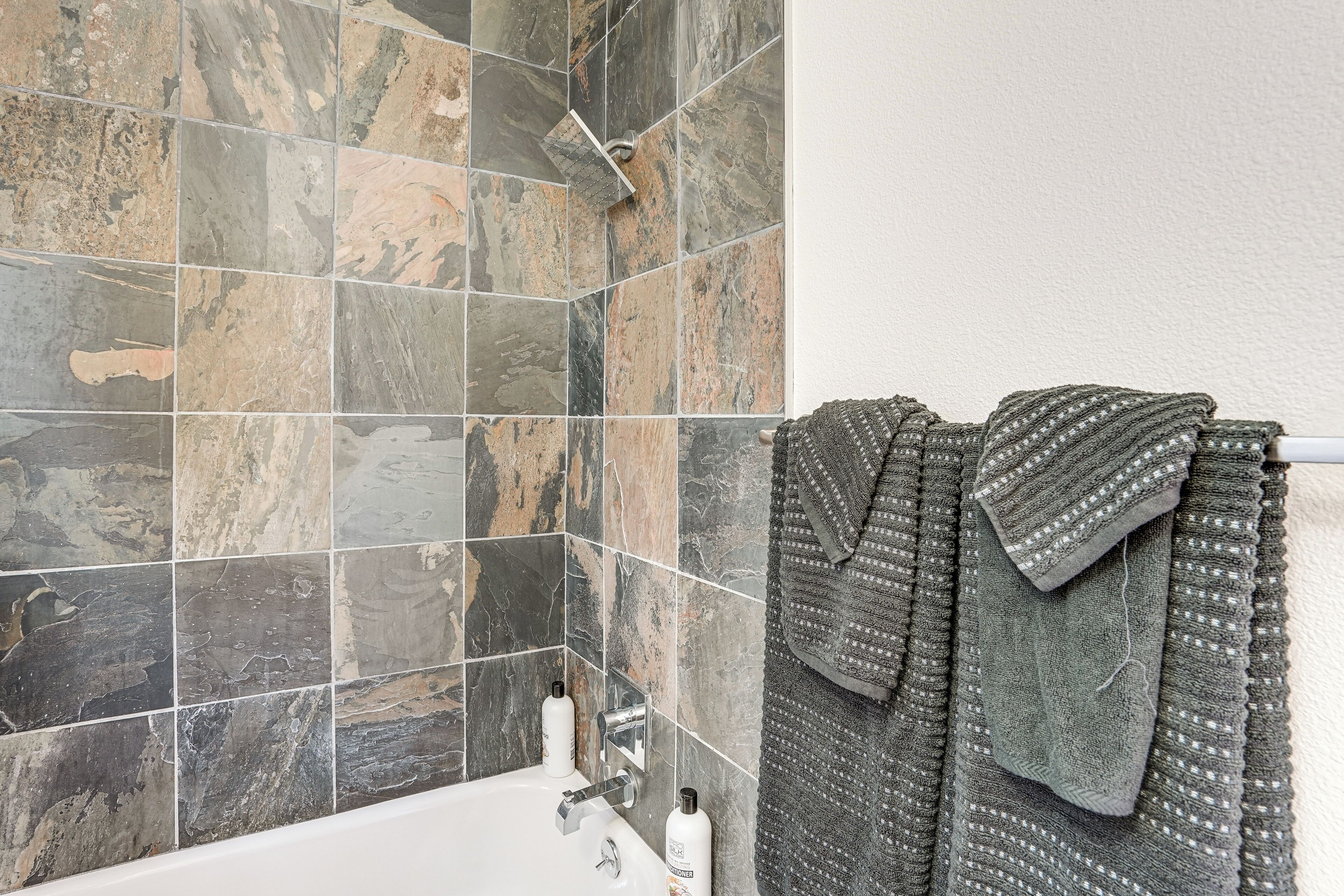 A bathroom with a bathtub, a shower, and a towel rack with towels.