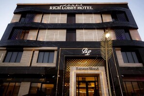 El exterior del Hotel Rich Lobby, con una entrada destacada y un cartel que indica que es un hotel de lujo.