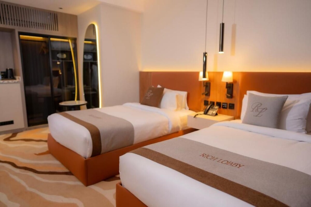 Habitación de hotel con dos camas, un minibar y vistas al exterior.