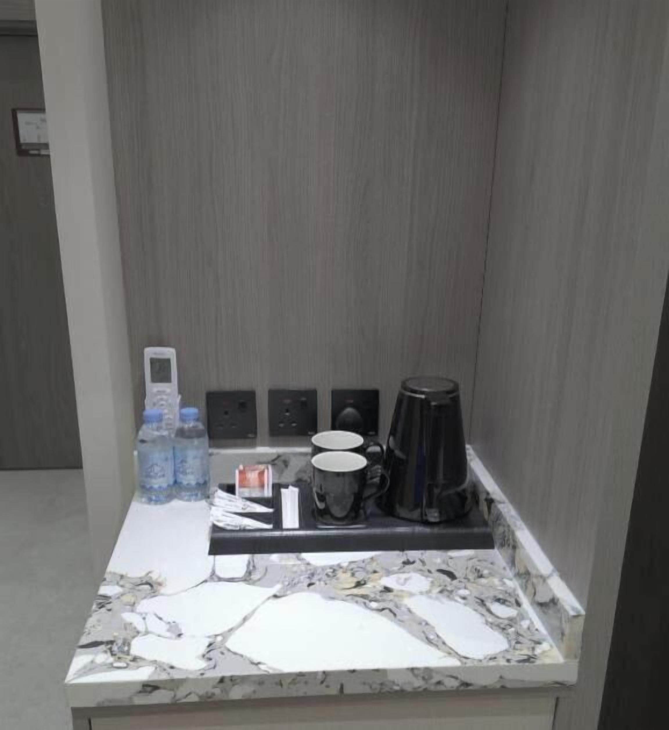 A small kitchenette with a marble countertop, a coffee maker, a kettle, and a water dispenser.