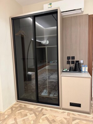 A hotel room with a sliding glass door closet, a small kitchenette with a coffee maker, and a tiled floor. - RICH LOBBY HOTEL HAIL (Ha'il)