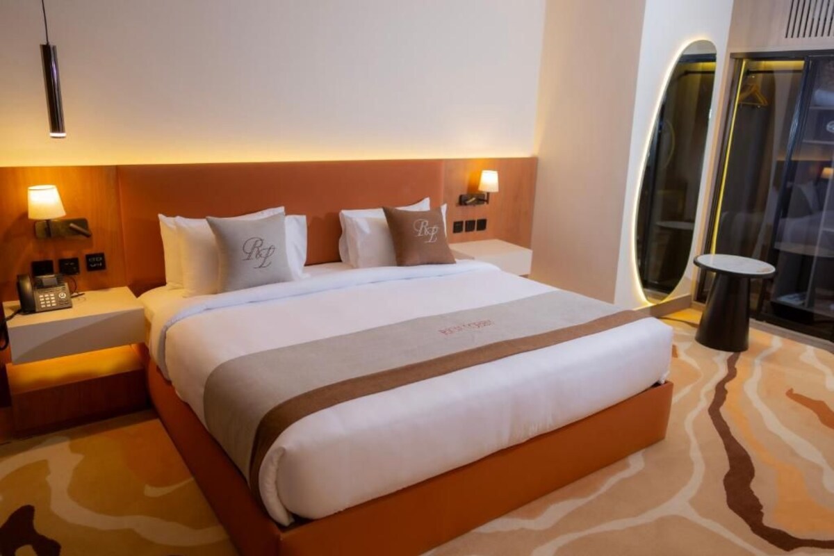 Habitación de hotel con una cama grande, mesitas de noche, una lámpara y vistas al exterior.