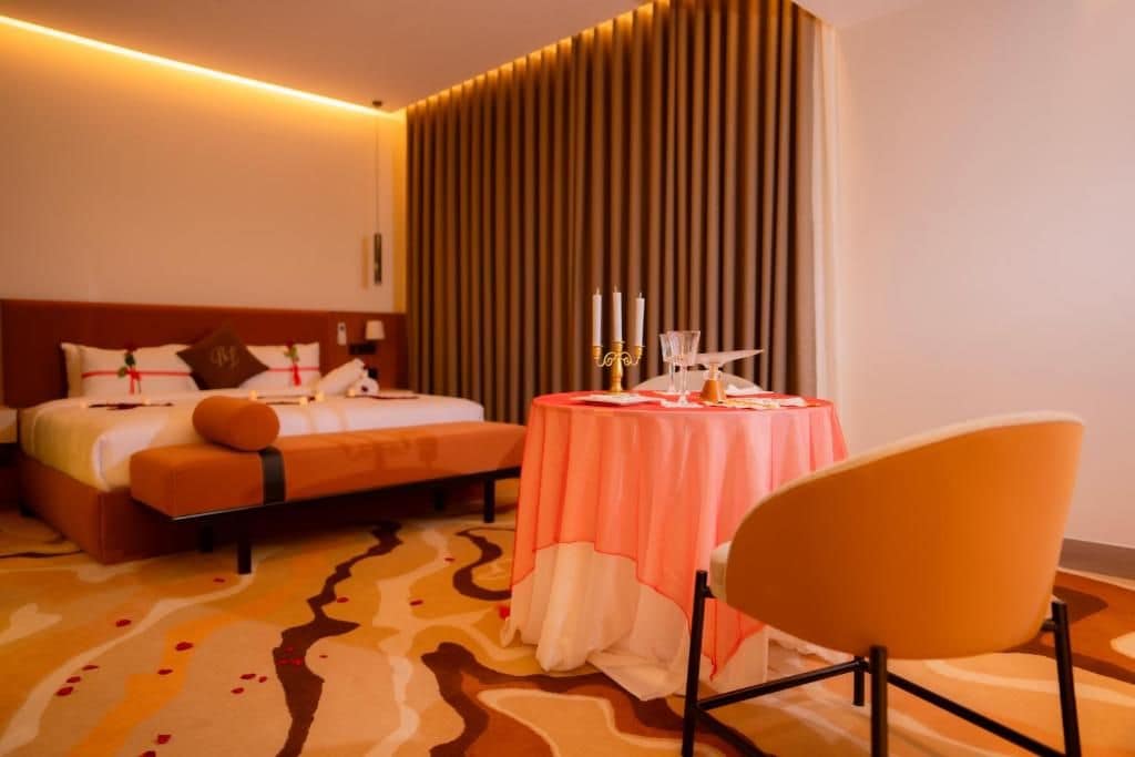 A hotel room with a bed, a round table with candles, and a chair.