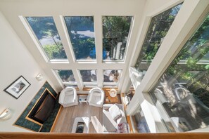 Una habitación con techos altos y un tragaluz grande, zona de estar con dos sillones, una mesita y vistas a zonas verdes.