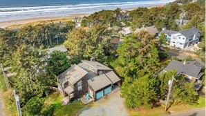 Una zona residenziale costiera con case, vegetazione rigogliosa e una spiaggia sullo sfondo.