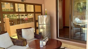 A balcony with a checkered floor, a refrigerator, and a table with a bottle. - Private 3BR Villa & Pool | Flic en Flac | 100% Privacy & 7Mins walk to the beach (Flic en Flac)