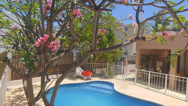 A swimming pool surrounded by a fence, with a chair and a red object nearby. - Private 3BR Villa & Pool | Flic en Flac | 100% Privacy & 7Mins walk to the beach (Flic en Flac)