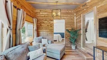 L’intérieur chaleureux d’un chalet, avec un décor en bois, un canapé, une petite table et une plante en pot.