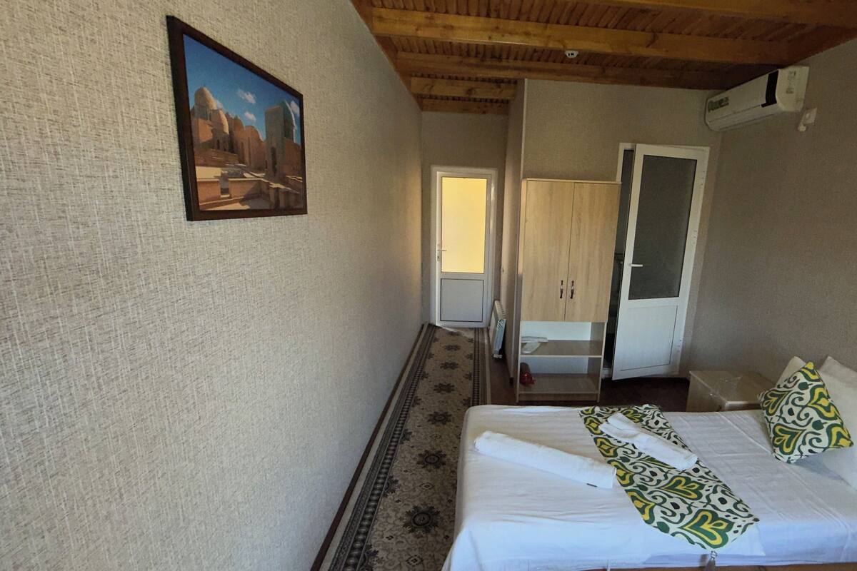 Ein Schlafzimmer mit Bett, einem Bild an der Wand, einem Kleiderschrank und einer Tür zu einem weiteren Raum.