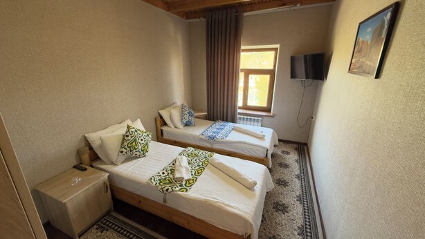 A room with two beds, a TV, and a window.