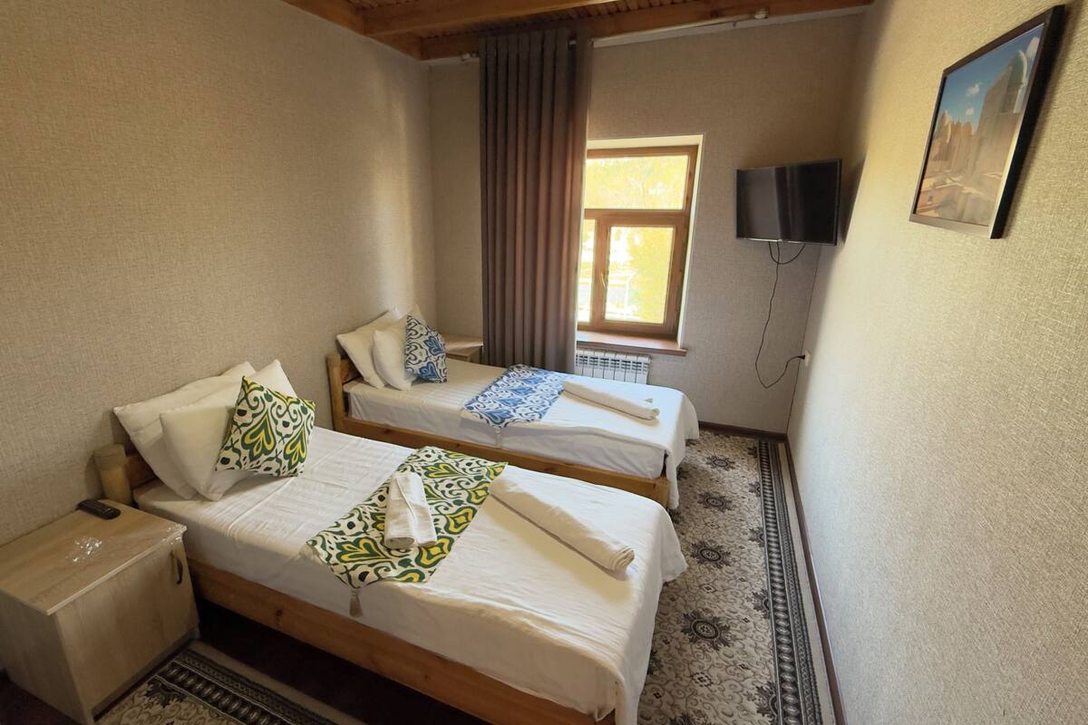 Ein Zimmer mit zwei Betten, einem Fernseher und einem Fenster.