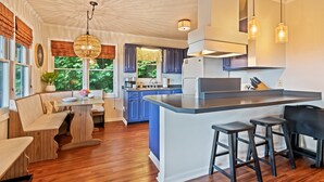 A modern kitchen with a central island, bar stools, and a dining area with a bench and table. - Peaceful Mountain Hideaway with a view, near Maggie Valley and Asheville (Waynesville)