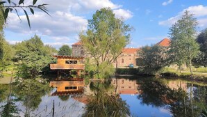 Un immobile sul fiume con struttura in legno, edificio in pietra e cielo sereno.