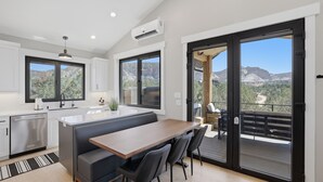 Een moderne keuken met een centraal eiland, grote ramen en een balkon met uitzicht op de bergen.