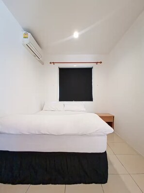 Ein Schlafzimmer mit Bett, Fenster, Nachttisch und Klimaanlage.