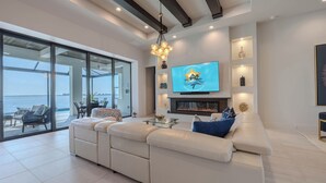 Ein modernes Wohnzimmer mit einer großen Couch, einem flachbildfernseher an der Wand und einem Kamin.