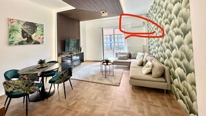Un soggiorno moderno con un divano, un tavolo da pranzo, sedie e una televisione.
