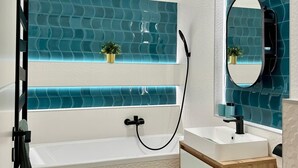 Un bagno moderno con vasca, lavandino, specchio e doccia.