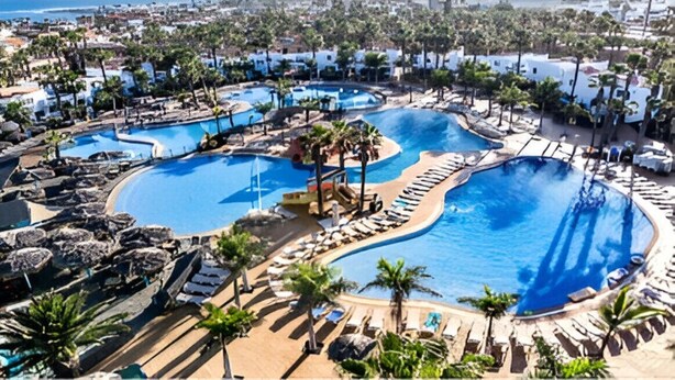 A resort with multiple swimming pools, lounge areas, and palm trees. - Air-conditioned apartment with 4 community pools - Corralejo - Pools view (Corralejo)