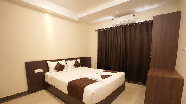 A hotel room with a large bed, a wardrobe, and an air conditioning unit. - Krishna Royal Club (Guruvayur)