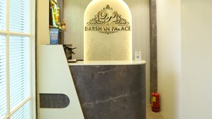 A reception desk with a sign reading 'DARSHAN PALACE,' a ceiling fan, and a fire extinguisher. - hotel Darshan Palace (Mumbai)