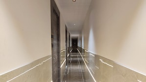 A long, narrow hallway with a shiny marble floor and light strips along the walls. - hotel Darshan Palace (Mumbai)