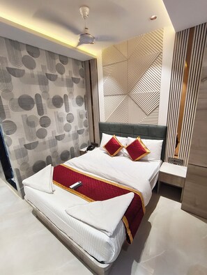 Una habitación de hotel moderna con una cama grande, una mesita de noche y un ventilador de techo.