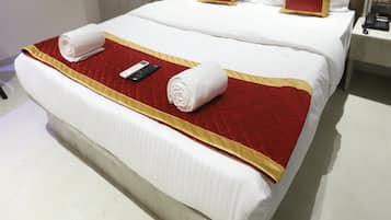 A hotel room with a large bed, a bedside table with a phone, and a wall-mounted air conditioning unit.