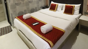 A hotel room with a large bed, a ceiling fan, and a patterned wall. - hotel Darshan Palace (Mumbai)