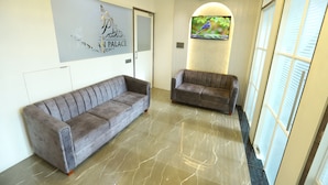 A reception area with two sofas, a wall-mounted TV, and a decorative wall piece. - hotel Darshan Palace (Mumbai)