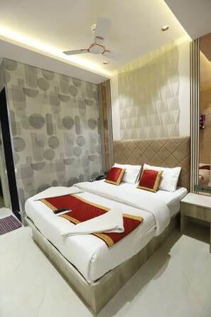 A modern hotel room with a large bed, a ceiling fan, and a patterned wall. - hotel Darshan Palace (Mumbai)