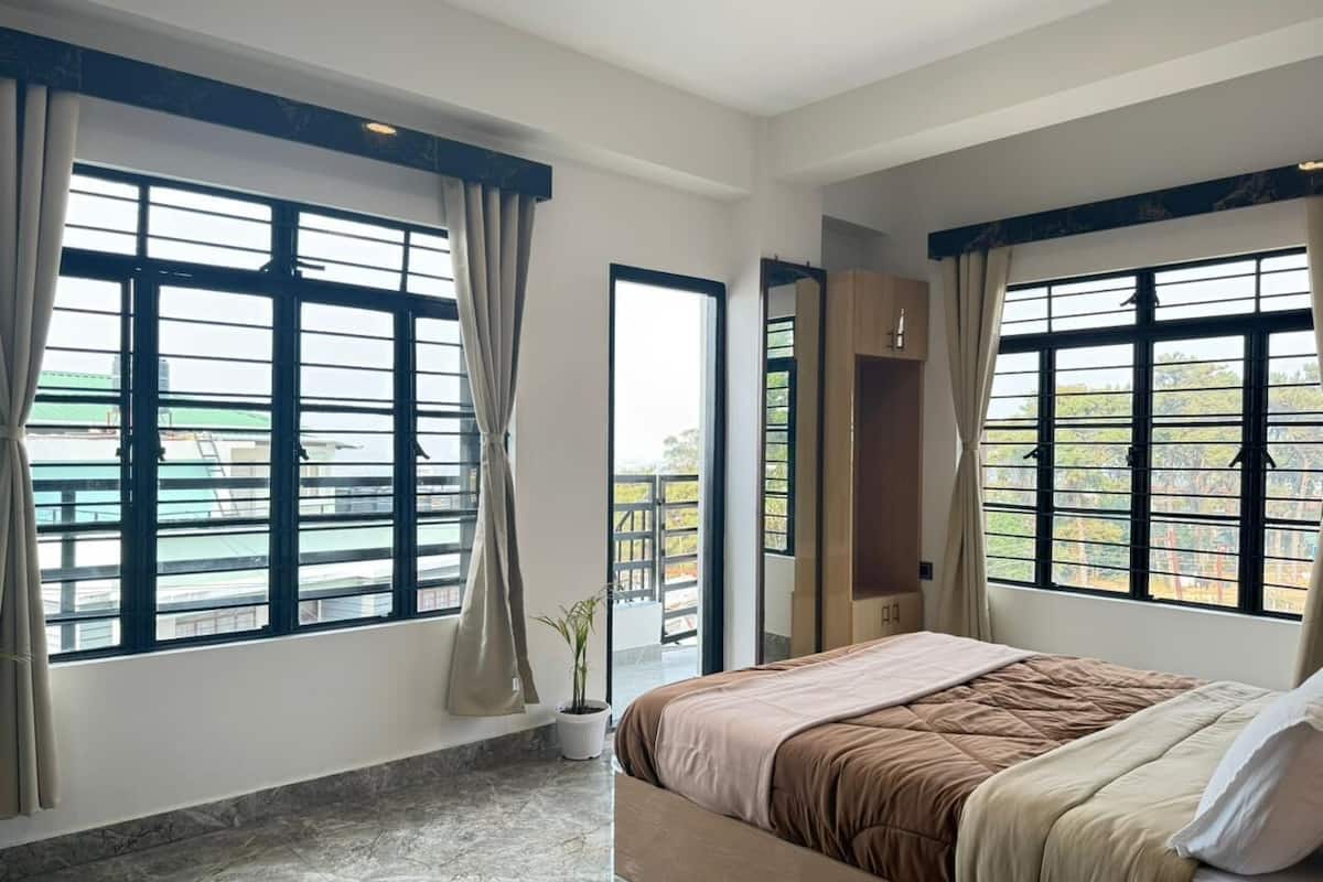 Un dormitorio con cama, ventanas grandes y vistas al balcón.
