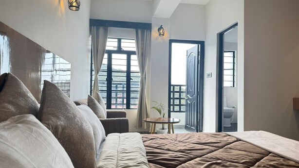 Una camera da letto con un letto grande, un tavolino con una pianta e vista all'esterno tramite una porta.