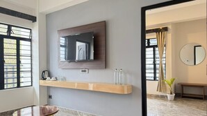 Una camera d'albergo moderna con pavimento in marmo, TV a parete, mensola in legno con articoli da toilette, un tavolino e una panca.