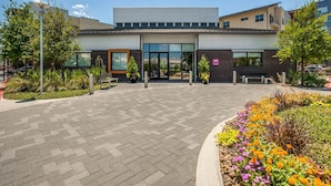 Un edificio moderno con un'ampia porta garage, una panchina e un'aiuola con diverse piante e fiori.