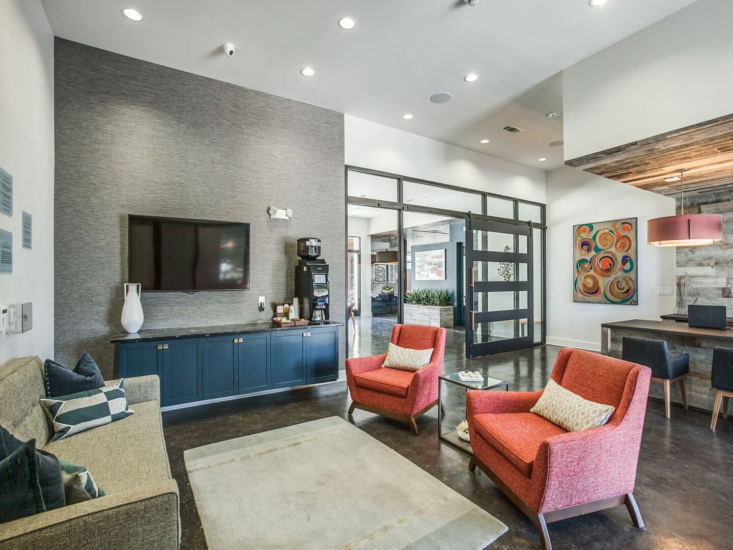 Una sala de estar moderna con televisor de pantalla plana, cafetera y comedor con mesa y sillas.