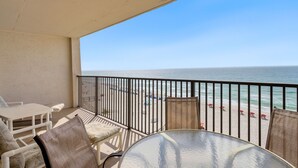 Un balcone con vista sulla spiaggia, un tavolo e delle sedie.