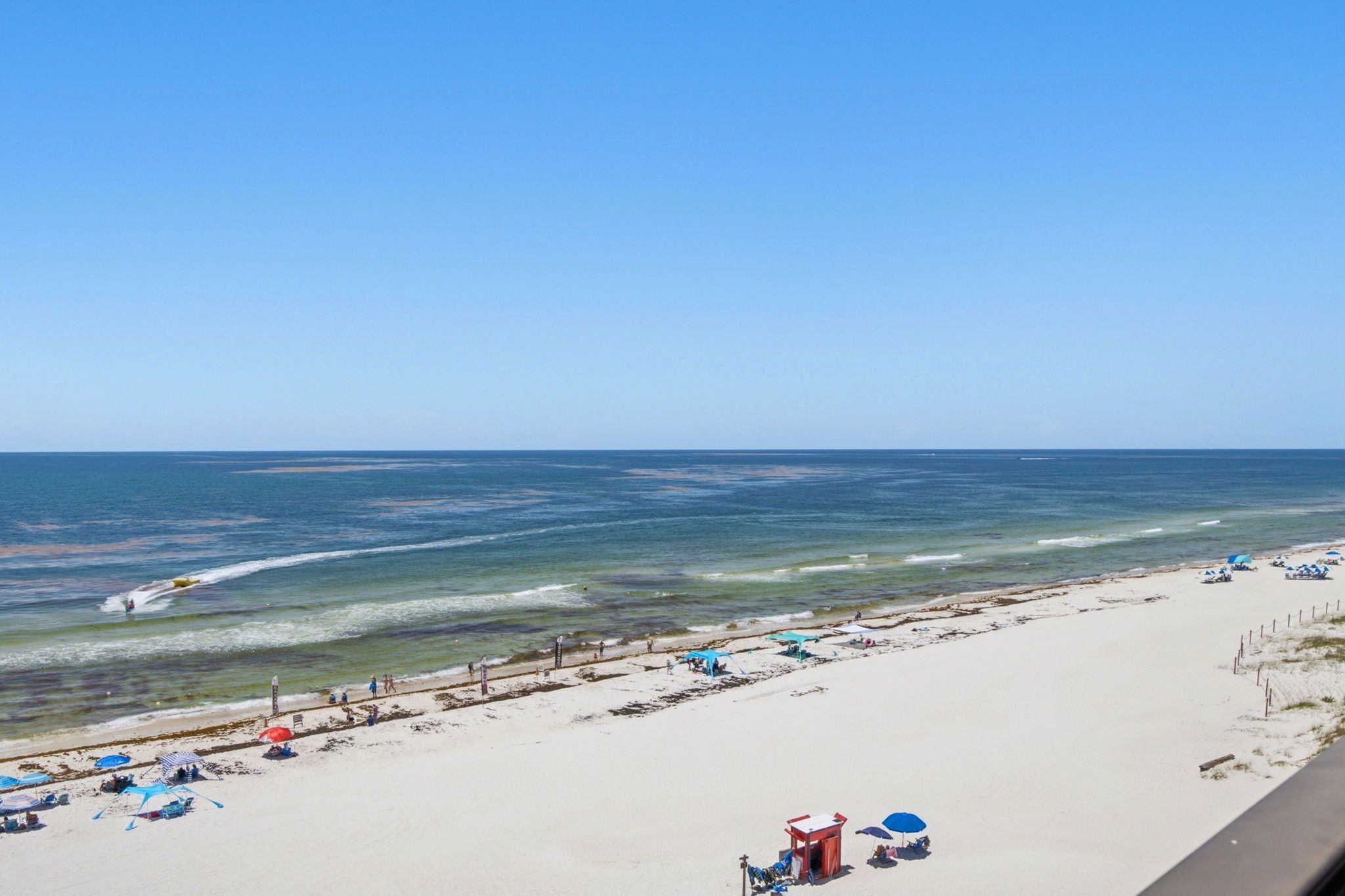 A beach with a clear sky, a sandy shore, and a few umbrellas.