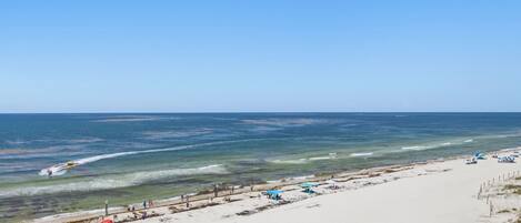 A beach with a clear sky, a sandy shore, and a few umbrellas.
