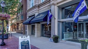 A building with 'The Liberty' signage, a brick facade, and large windows. - Landing Furnished Apartments near YSM (New Haven)