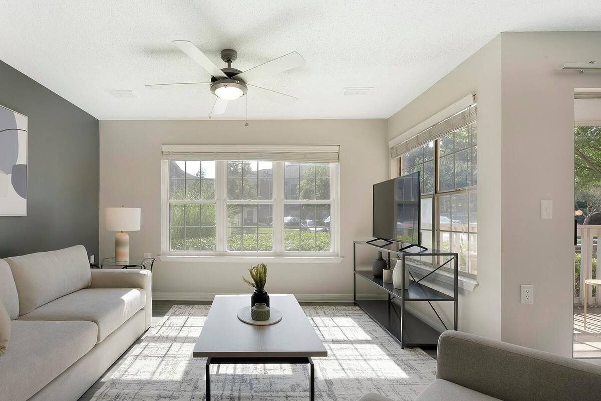 Un salon avec un canapé, une table basse, un téléviseur et un ventilateur de plafond.
