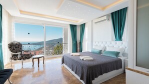 A bedroom with a large bed, a chair, a balcony with a view, and a ceiling with recessed lighting. - Stunning Sea View Villa in Kalkan with Private Pool, 4 Bedrooms, 8 Guests (Antalya)