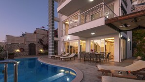 A poolside area with lounge chairs, a dining table, and a staircase leading to a balcony. - Stunning Sea View Villa in Kalkan with Private Pool, 4 Bedrooms, 8 Guests (Antalya)