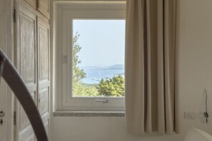 Una habitación con ventana que da a un paisaje, una puerta y un enchufe en la pared.