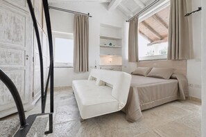 Ein Schlafzimmer mit Bett, Sofa, Fenster und Regaleinheit.