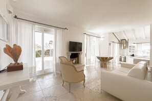 Ein geräumiges Wohnzimmer mit Kamin, Fernseher und Essbereich mit Tisch und Stühlen.