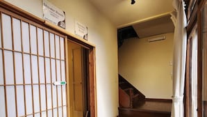 Una habitación de estilo japonés tradicional, con suelo de tatami, una puerta corredera y una escalera que sube a otro nivel.